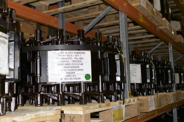 Ein Lagerraum voller metallener Objekte auf Holzpaletten, jedes mit einem Aufkleber, die Teil eines Verteilergehäuses zu sein scheinen, mit verschiedenen sichtbaren Komponenten.