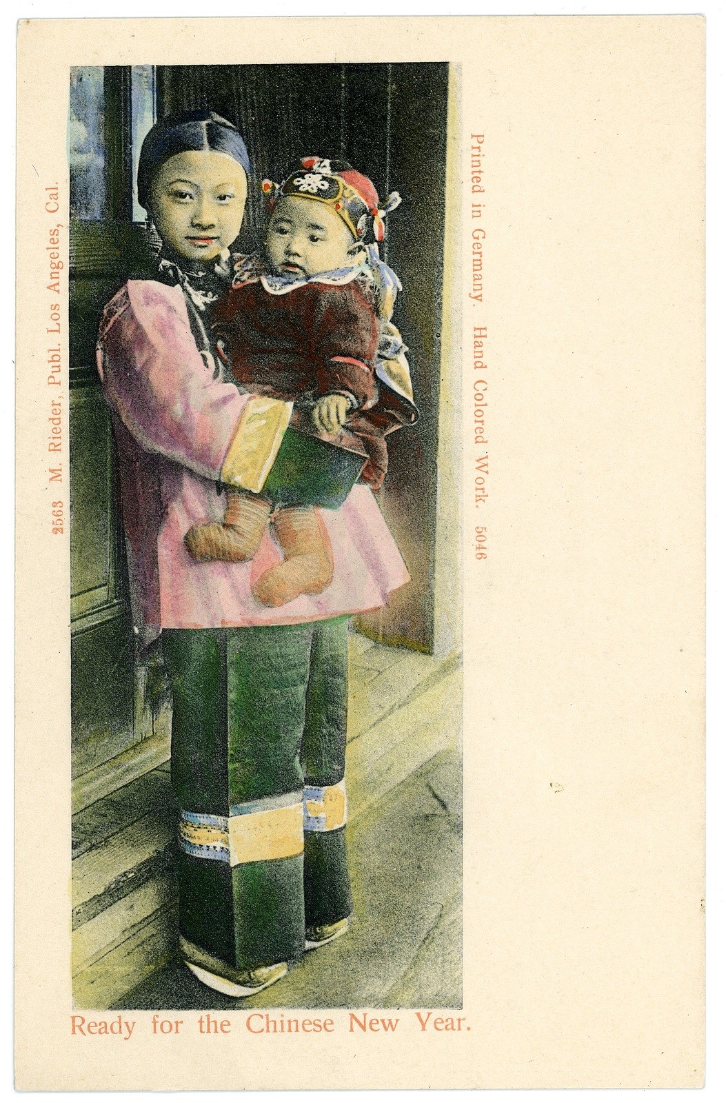 Eine sepiafarbene Postkarte mit einer Frau, die ein Baby im Arm h├Ąlt und beide warm l├Ącheln, mit Text, der wahrscheinlich einen glücklichen neuen Jahr gewünscht.