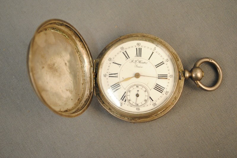 Eine silberne Taschenuhr mit einem weißen Zifferblatt mit römischen Zahlen auf einem grauen Hintergrund, mit einem Deckel für einen klassischen Look.