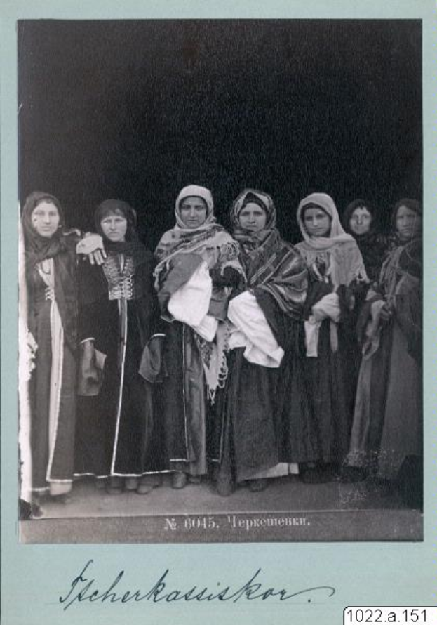 Eine Gruppe von Frauen in traditioneller russischer Kleidung, einschließlich Kopftuch und Schmuck, posiert zusammen lachend vor der Kamera auf einem Schwarz-Weiß-Foto, mit dem Text "Orthodoxe russische Frauen" unten.