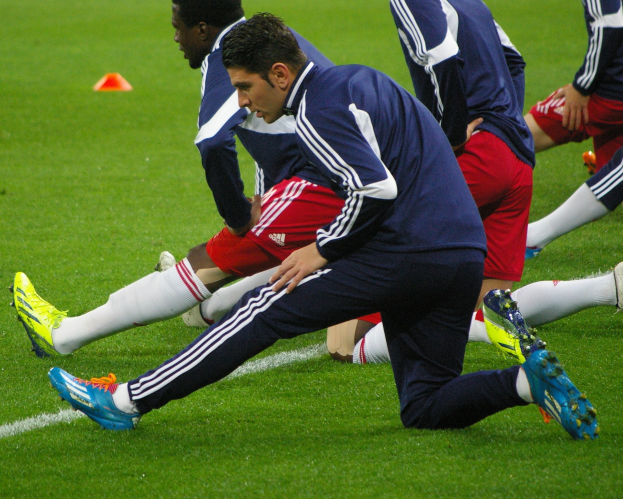 Gruppe von Männern in Sportkleidung, die während eines Trainings auf einem Rasenfußball spielen.