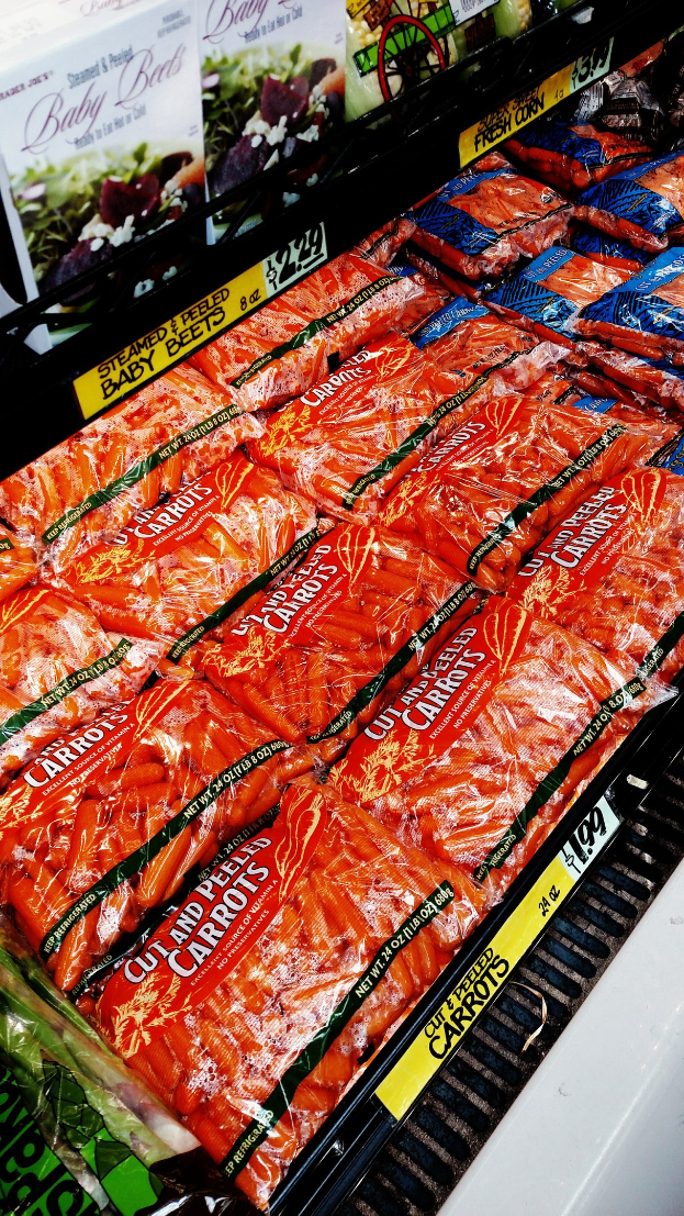 Ein Supermarktregal mit verschiedenen verpackten Lebensmitteln, darunter Gemüsepackungen, jeweils mit angebrachten Preisschildern.