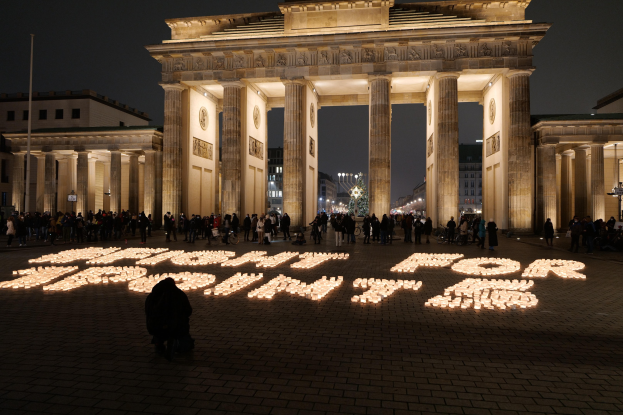 Eine Gruppe von Menschen, die vor dem beleuchteten Reichstagsgebäude in Berlin, Deutschland, mit 'Kampf für die Freiheit' auf dem Boden im Vordergrund stehen.