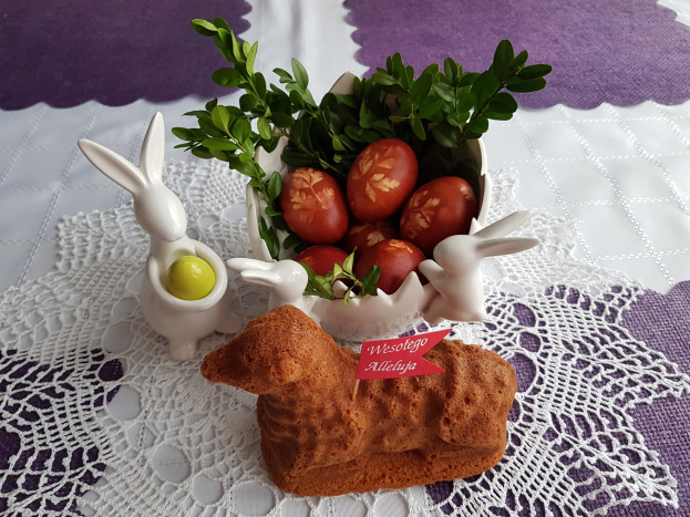 Ein Tisch mit einer Decke darauf hält eine Schüssel mit bunten Ostereiern und Osterhasen-Figuren darauf.