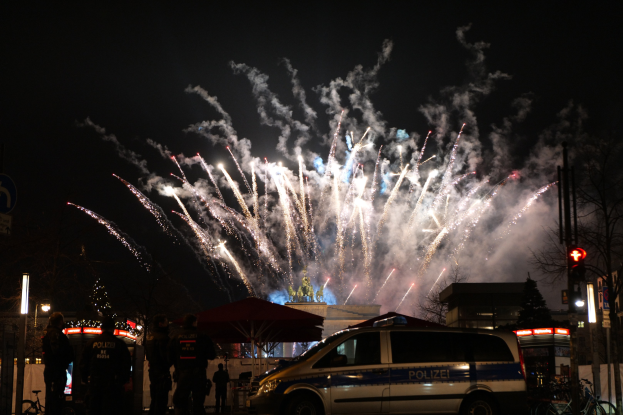 Ein Polizeiwagen vor einer Menschenmenge geparkt, die den Neujahrsabend in Berlin feiert.