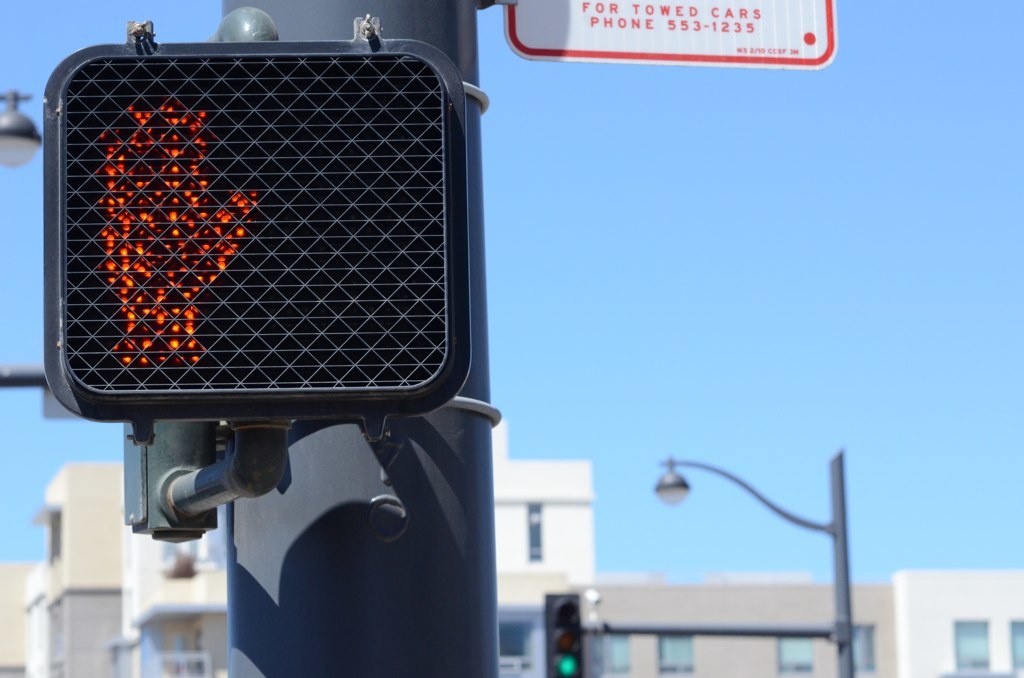 Eine Stadtstraßenszene mit Verkehrspfölen, Ampeln, Straßenpflölen, Straßenlaternen, Gebäuden und einem klaren Himmel.