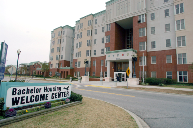 Außenansicht eines Bachelor-Wohnheim-Empfangszentrums mit Gebäuden, Straßeninfrastruktur, Fahrzeugen, Grünflächen und einem klaren Himmel.