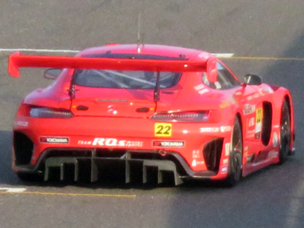 Roter Porsche 911 GTS Rennwagen auf einer Rennstrecke mit aerodynamischem Design, großer Heckflosse und schwarzen Rädern.