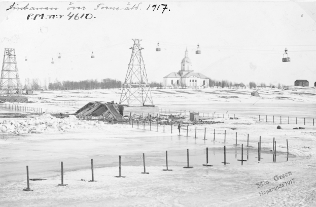 Schwarzes und weißes Foto einer Skipiste im Schnee mit Stützen und Türmen, Häusern, Bäumen und einem Gebäude im Hintergrund, mit Text oben.