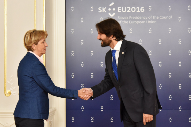 Bundeskanzlerin Angela Merkel und Bundeskanzler Joachim Gauck schütteln sich bei einem EU-Gipfeltreffen die Hände und lächeln.