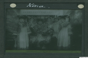 Ein Schwarz-Weiß-Foto einer Gruppe von Menschen in traditioneller chinesischer Kleidung, einige sitzen und einige stehen, mit Text oben.