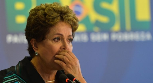 Brasiliens Präsidentin Dilma Rousseff spricht bei einer Pressekonferenz in Rio de Janeiro vor einer Tafel mit Text und Mikrofonen im Bild unten.