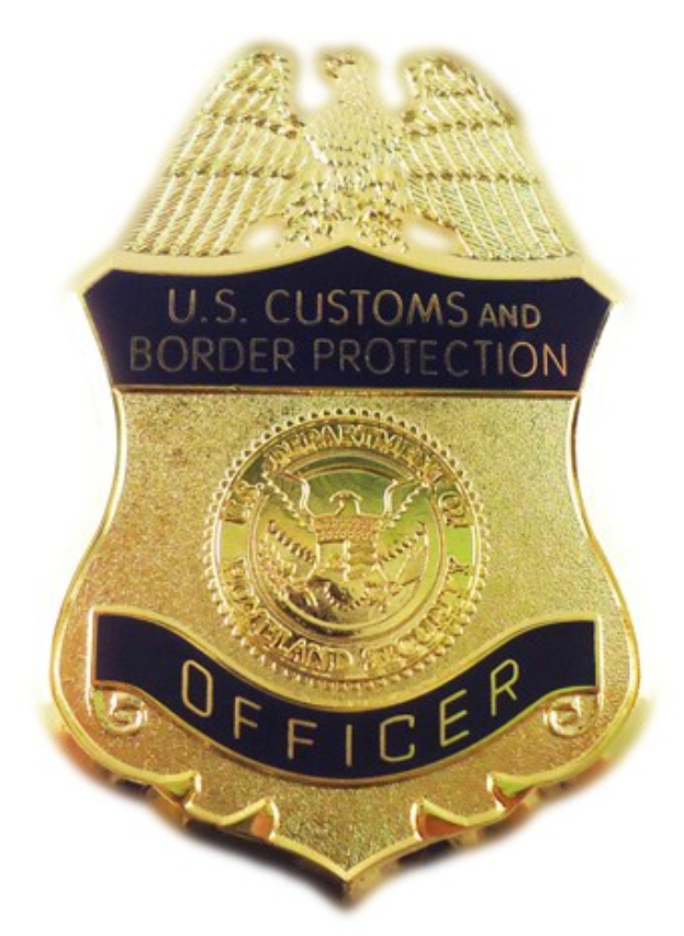 Goldes Abzeichen mit der Gravur "U.S. Customs and Border Protection Officer" vor einem weißen Hintergrund.