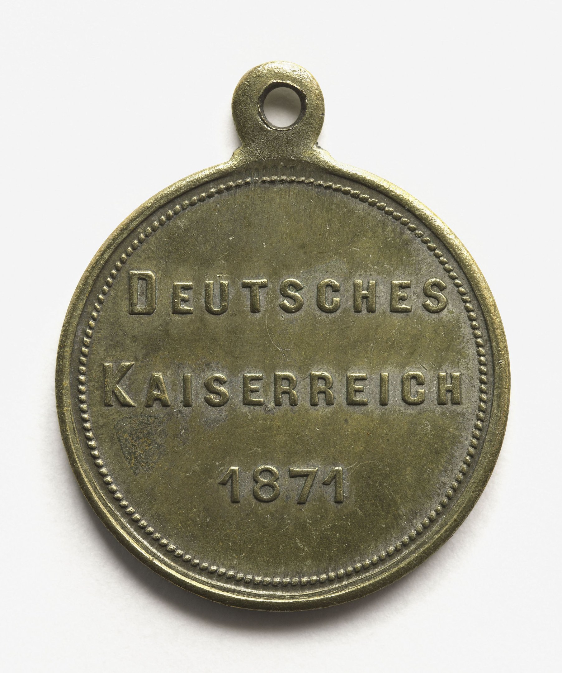 Bronzene Medaille mit der Inschrift "Deutsches Kaiserreich 1871" vor einem weißen Hintergrund.
