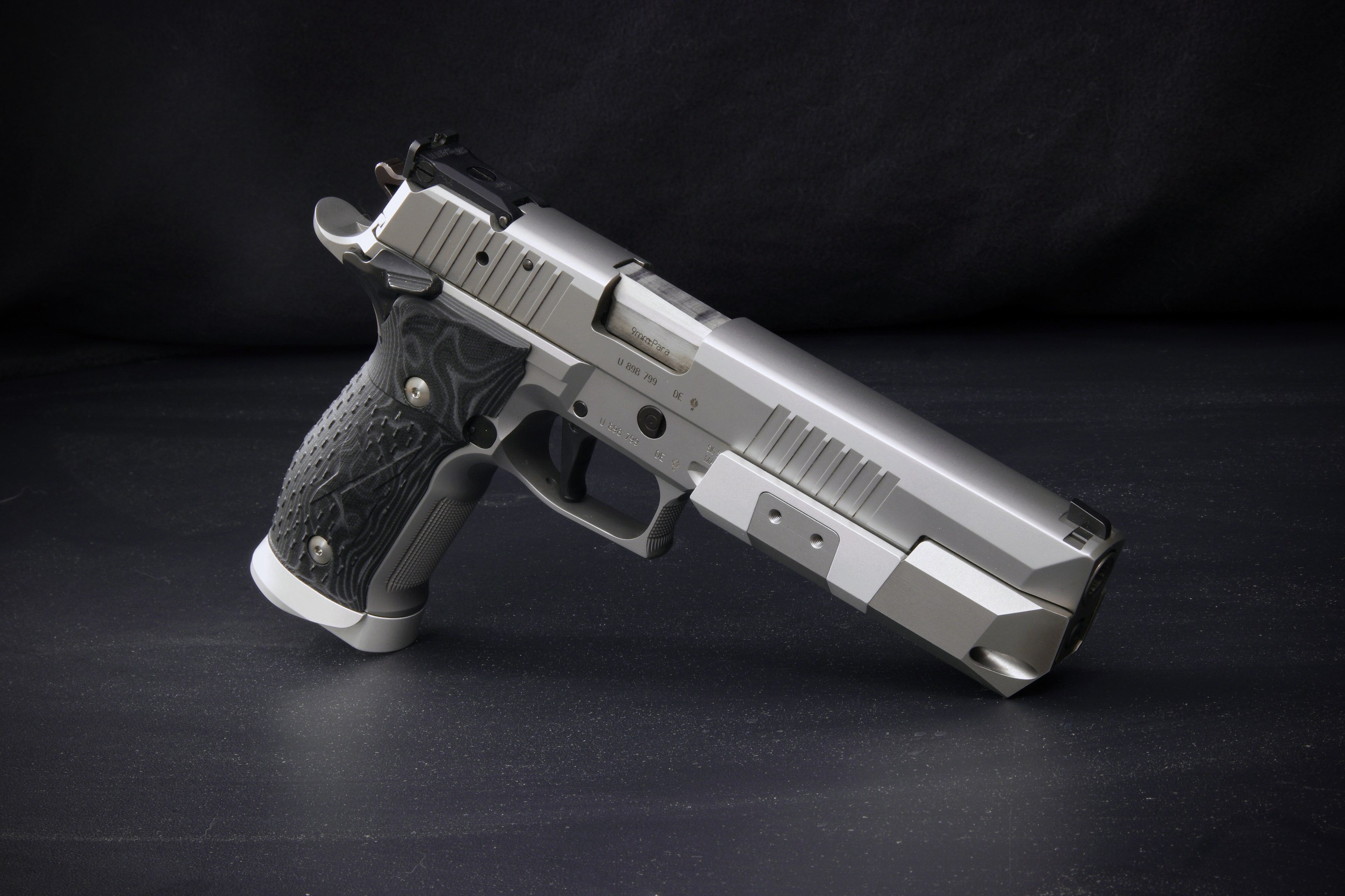 Sig Sauer P226 X-Five 9mm Pistole auf einer schwarzen Oberfläche mit schwarzem Hintergrund.