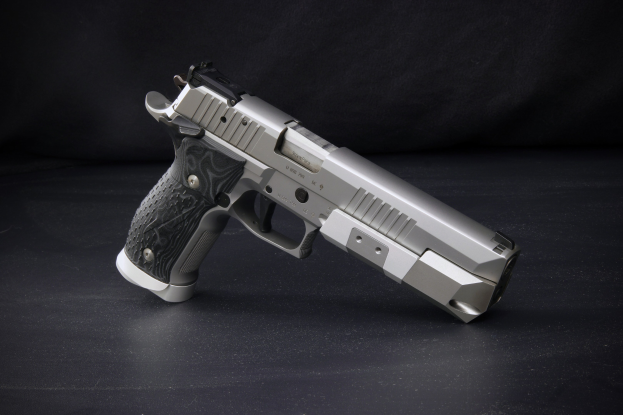 Sig Sauer P226 X-Five 9mm Pistole auf einer schwarzen Oberfläche mit schwarzem Hintergrund.